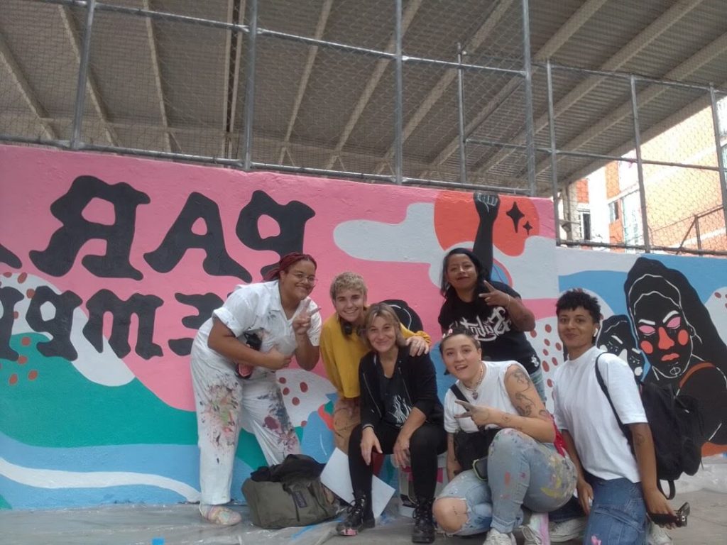 Ale con compañeras y compañeros de trabajo en un mural