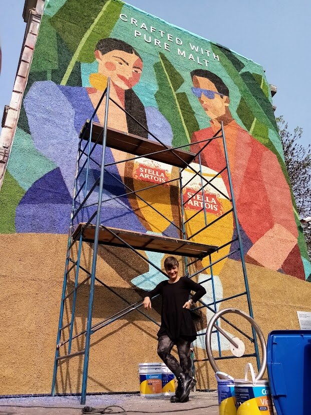 Alessandra Carughi posa junto a un andamio detrás de un mural